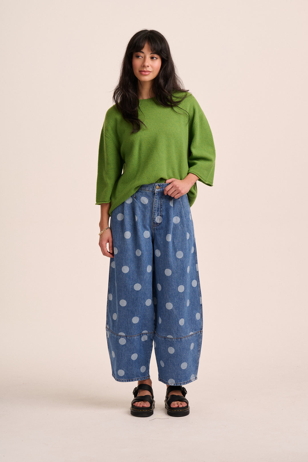  Model wearing mid-blue polka dot barrel-leg jeans with a green knit jumper and black sandals
