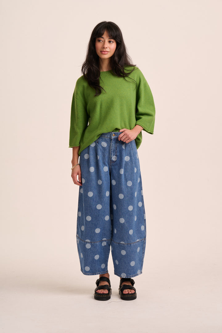  Model wearing mid-blue polka dot barrel-leg jeans with a green knit jumper and black sandals