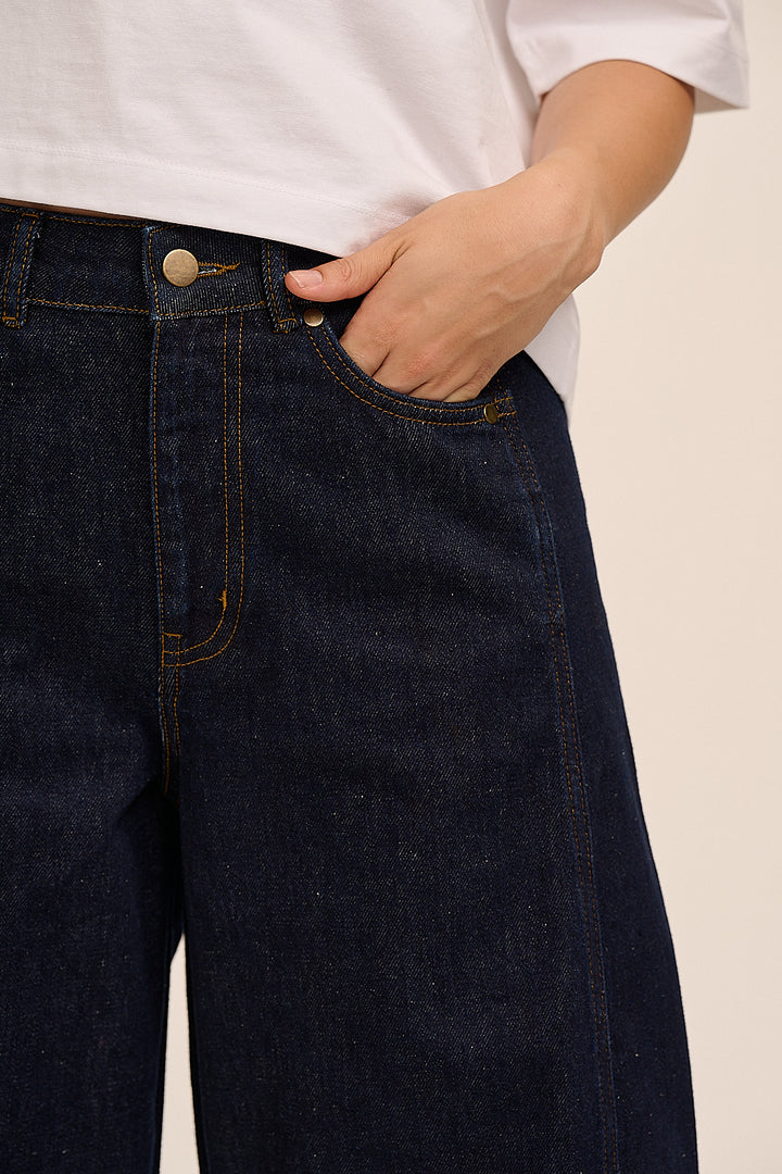 High-waisted indigo barrel jeans styled with white tee and trainers