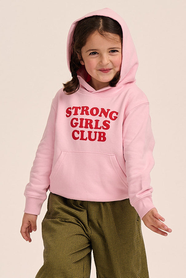 Child wearing a pink 'Strong Girls Club' hoodie with green pants on a beige background